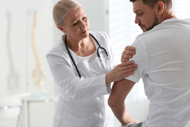 Photo of Male orthopedist examining patient's arm in clinic