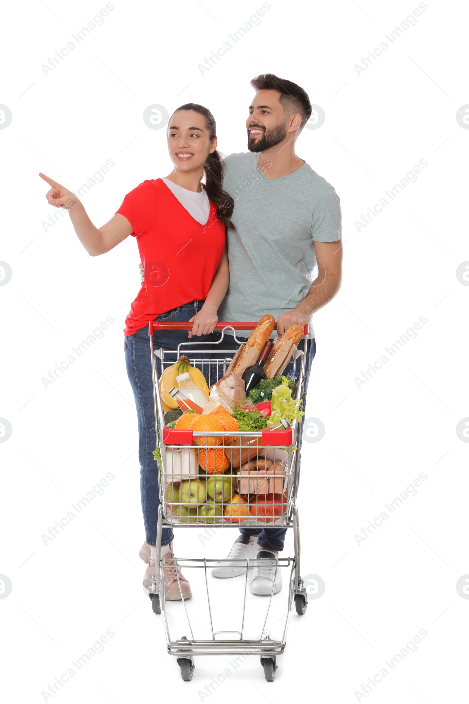 Photo of Happy couple with shopping cart full of groceries on white background