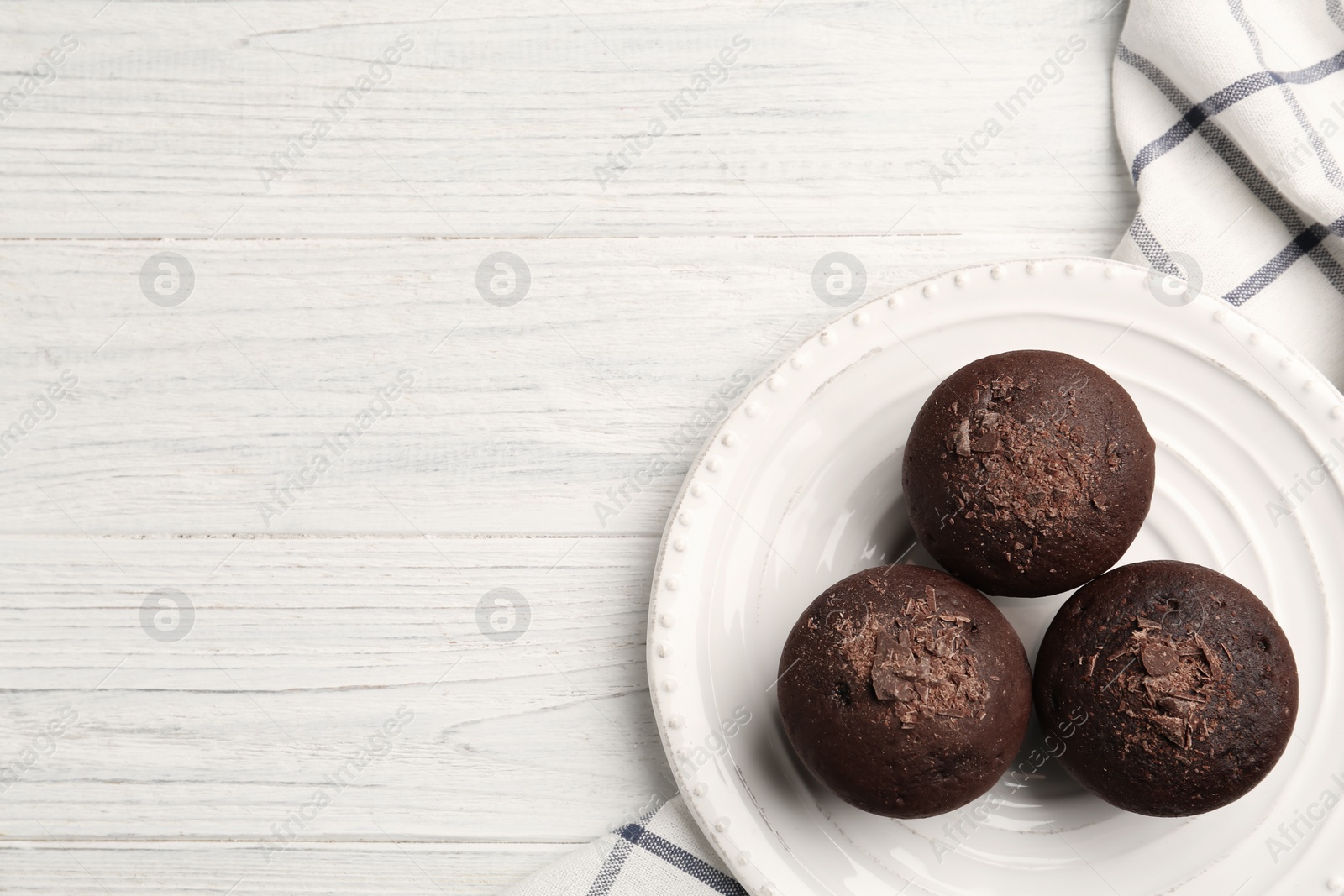 Photo of Delicious chocolate muffins on white wooden table, top view. Space for text