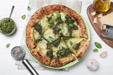Photo of Delicious pizza with pesto, cheese and basil served on white wooden table, flat lay