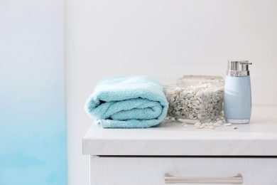Photo of Soap dispenser, sea salt and towel on bathroom counter