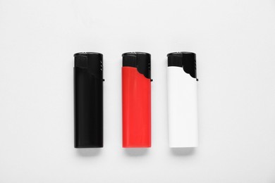 Photo of Stylish small pocket lighters on white background, flat lay