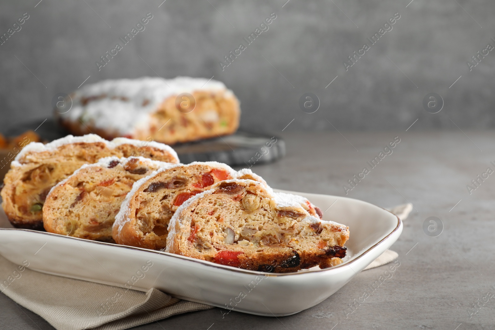 Photo of Traditional Christmas Stollen with icing sugar on grey table