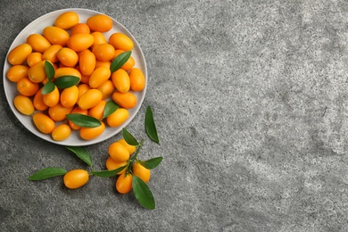 Photo of Fresh ripe kumquats on grey table, flat lay. Space for text