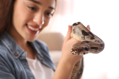 Young woman with her boa constrictor at home, focus on hand