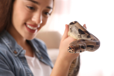 Photo of Young woman with her boa constrictor at home, focus on hand