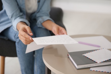 Photo of Young woman reading paper letter at home, closeup