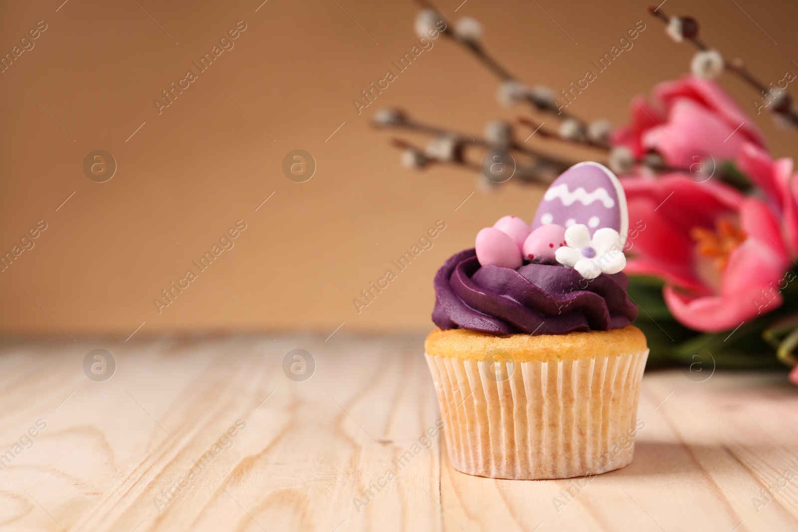 Photo of Tasty cupcake with Easter decor on wooden table, space for text