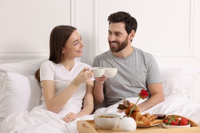 Photo of Happy couple having tasty breakfast in bed at home