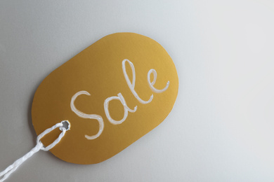 Golden tag with word SALE on light grey background, top view. Black Friday concept