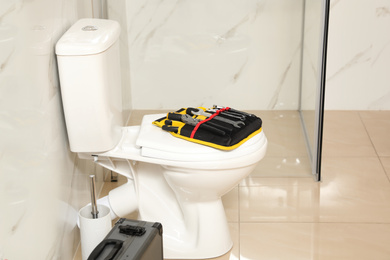 Photo of Plumber's tools on toilet bowl in bathroom