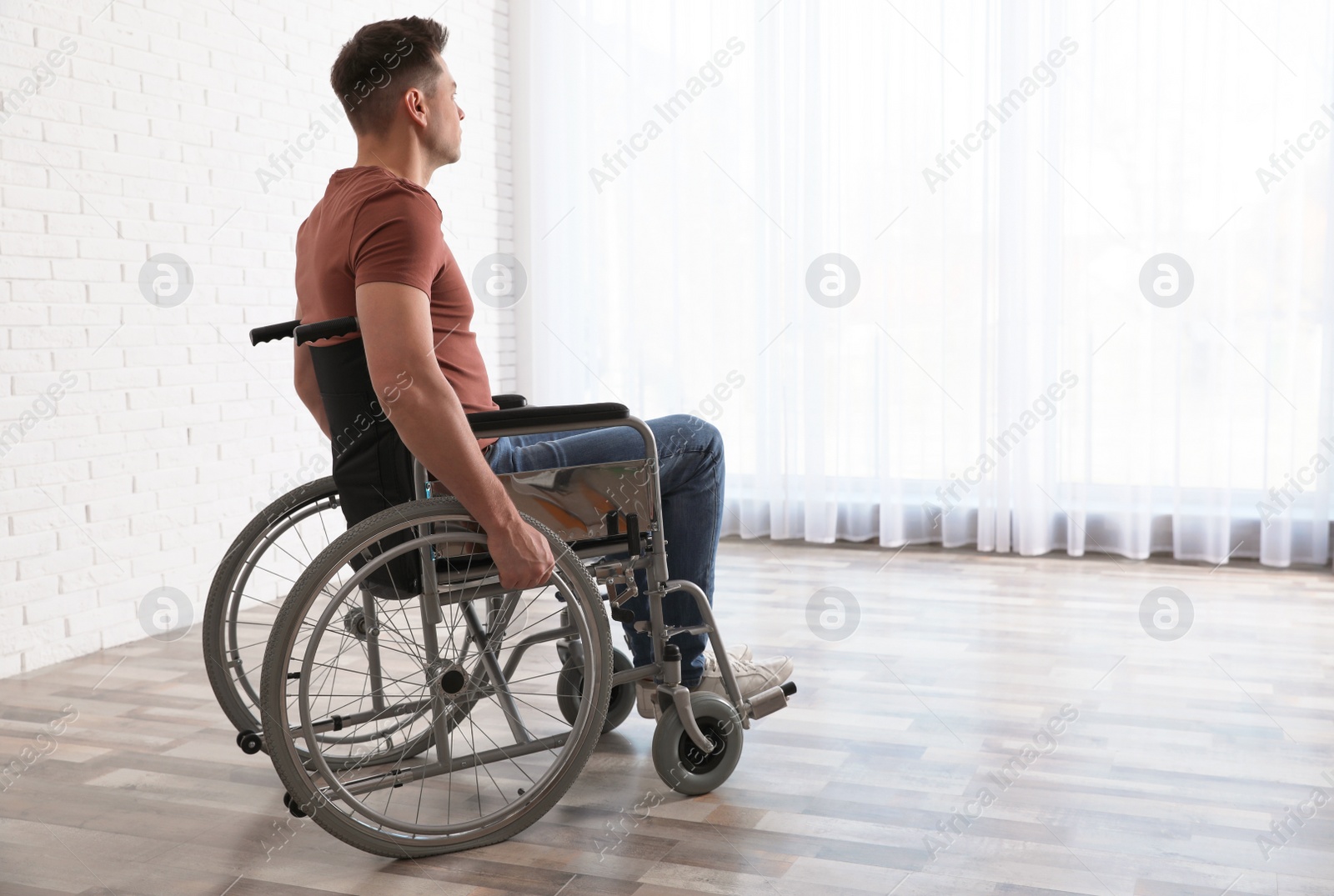 Photo of Thoughtful man sitting in wheelchair near window at home