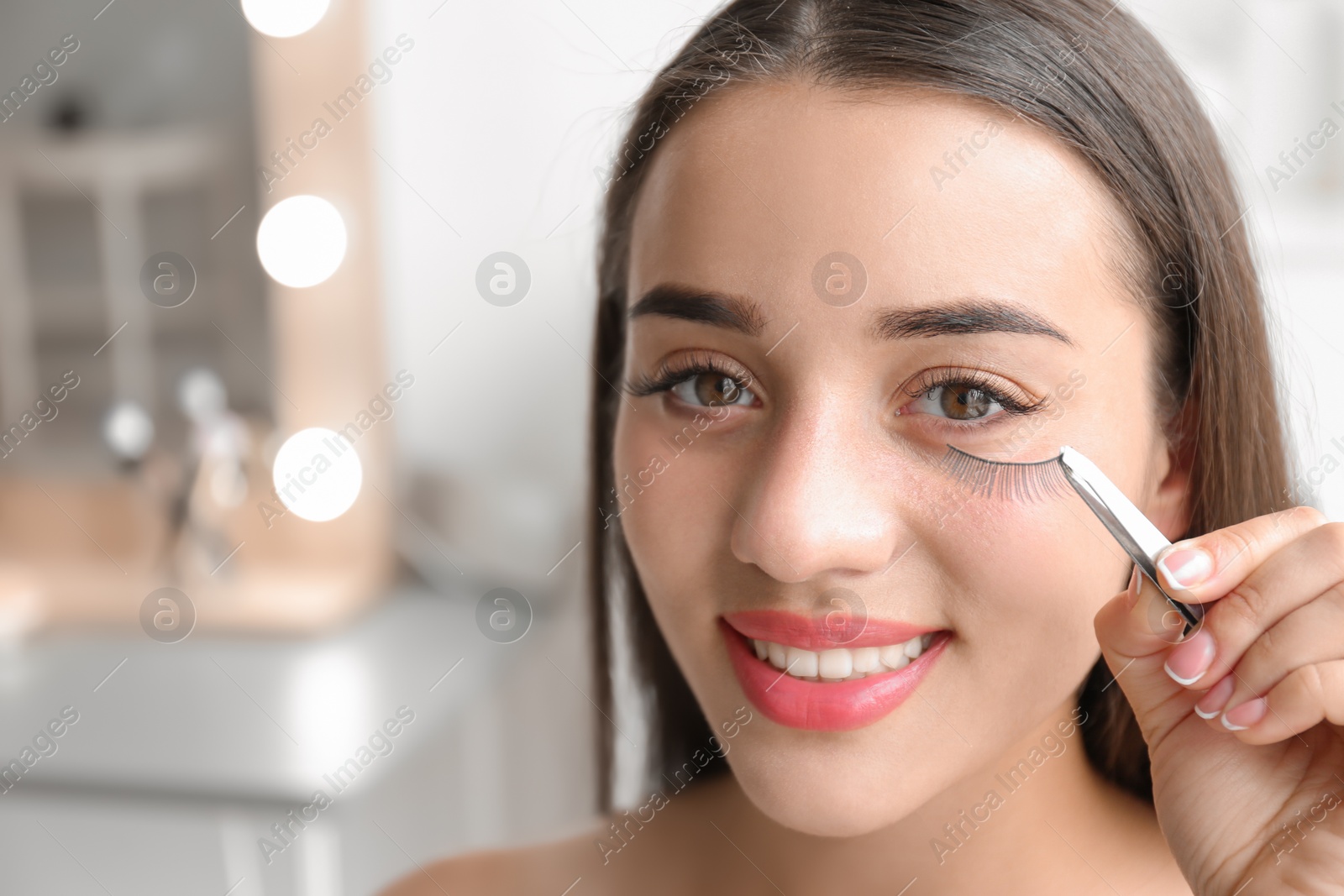 Photo of Attractive young woman with false eyelashes on blurred background