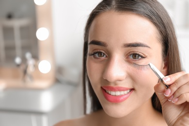 Attractive young woman with false eyelashes on blurred background