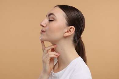 Photo of Beautiful woman touching her chin on beige background