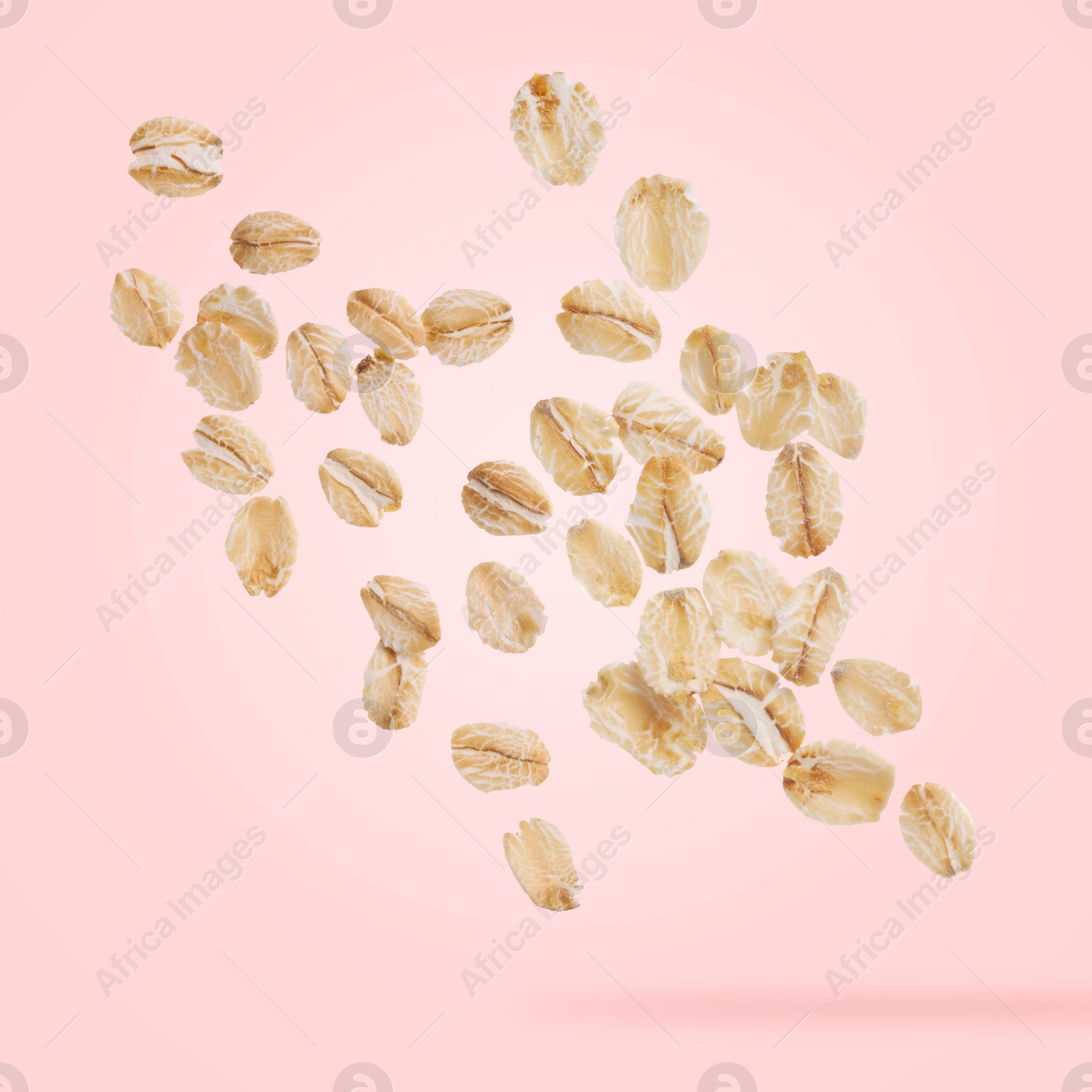 Image of Rolled oat flakes falling on pink background