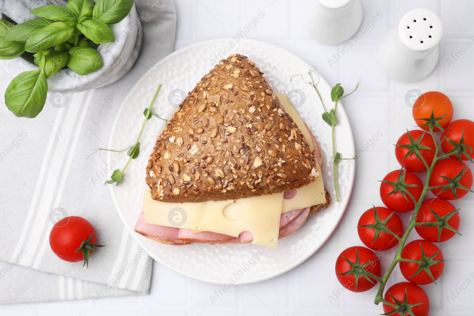Photo of Delicious sandwich with ham, cheese and products on white table, flat lay