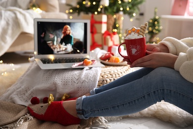 Photo of MYKOLAIV, UKRAINE - DECEMBER 25, 2020: Woman with sweet drink watching The Queen's Gambit series on laptop at home, closeup. Cozy winter holidays atmosphere