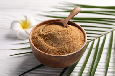 Coconut sugar and spoon in bowl on white wooden table, closeup