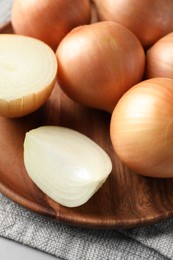 Photo of Whole and cut onions on table, closeup