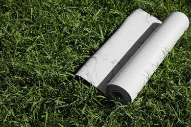 Karemat or fitness mat on green grass outdoors, space for text