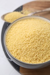 Photo of Raw couscous in bowl on table, closeup