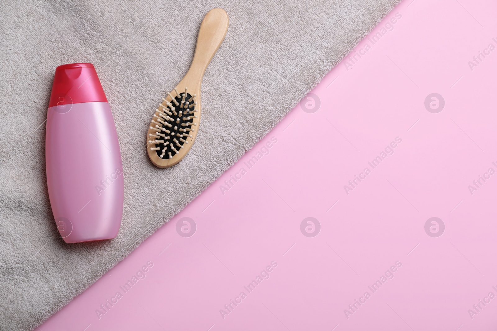 Photo of Bottle of shampoo, towel and brush on color background, top view with space for text