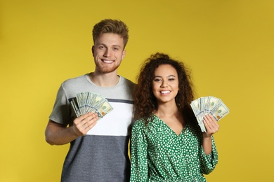 Photo of Young couple with money on color background