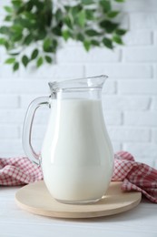 Jug of fresh milk on white wooden table