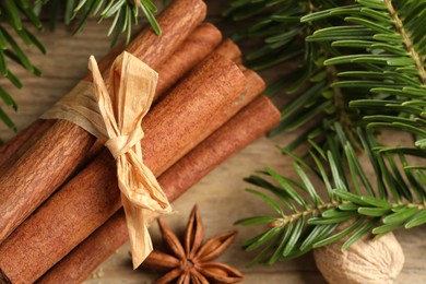 Different aromatic spices and fir branches on wooden table, top view