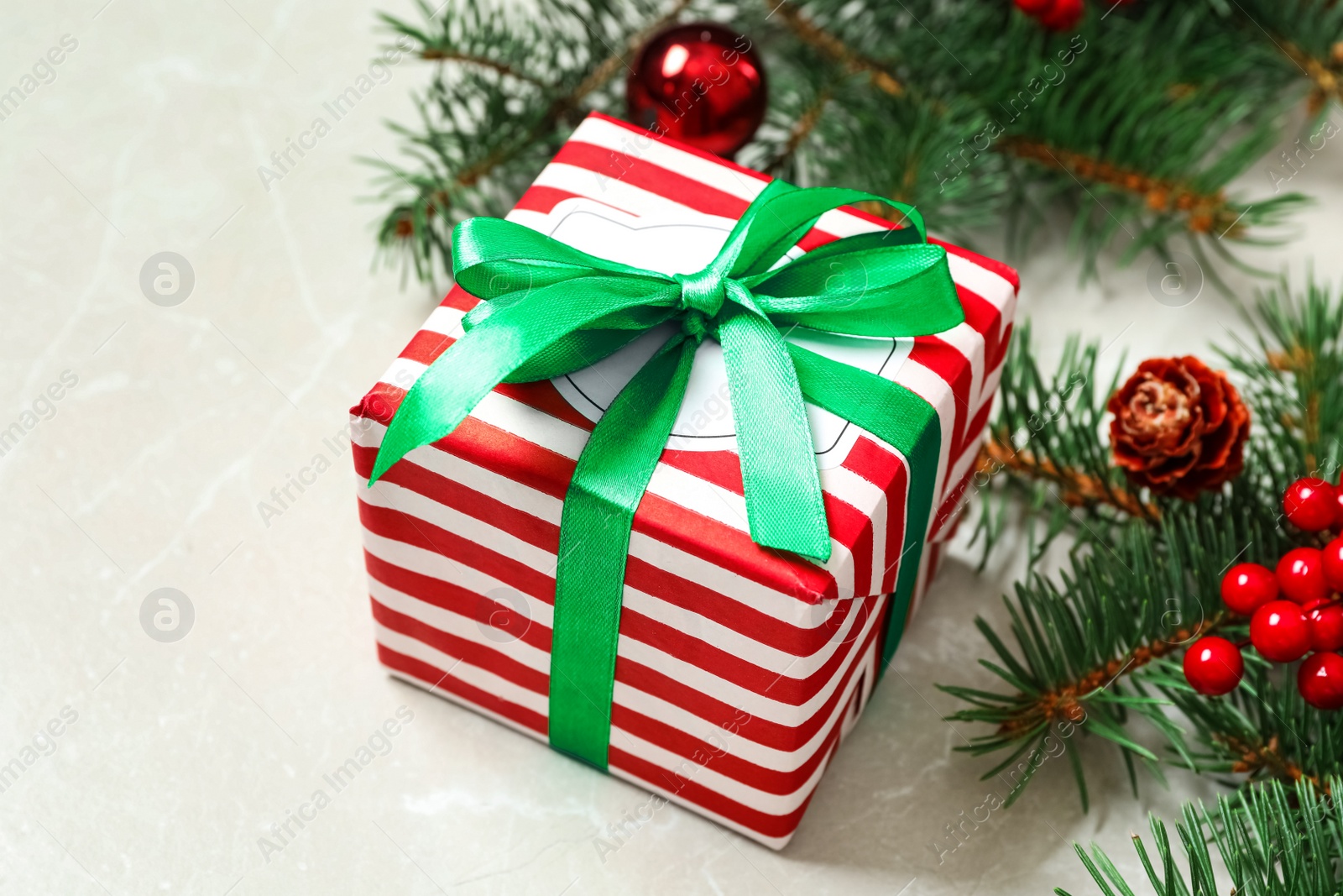 Photo of Christmas gift box with green bow and festive decor on light table