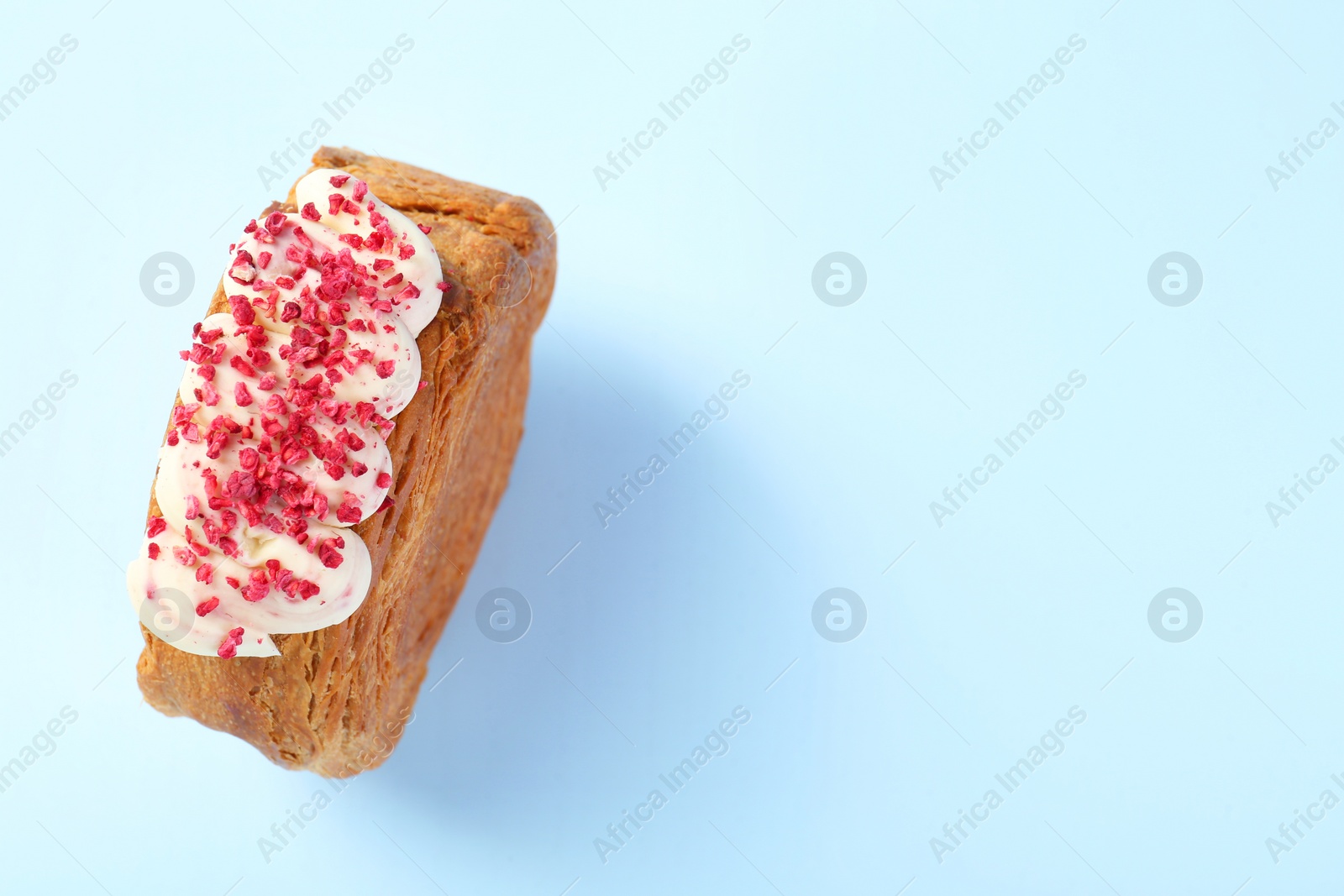 Photo of One supreme croissant with cream on light blue background, above view with space for text. Tasty puff pastry
