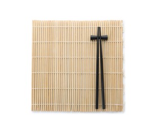 Photo of Bamboo mat with pair of black chopsticks and rest isolated on white, top view
