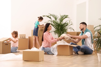 Photo of Happy family unpacking moving boxes in new house
