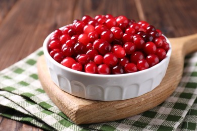 Fresh ripe cranberries in bowl on wooden table, closeup