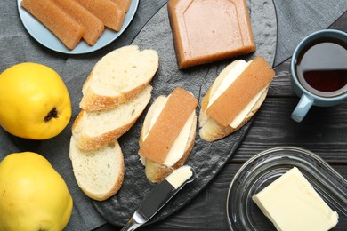 Photo of Tasty sandwiches with quince paste served on black wooden table, flat lay
