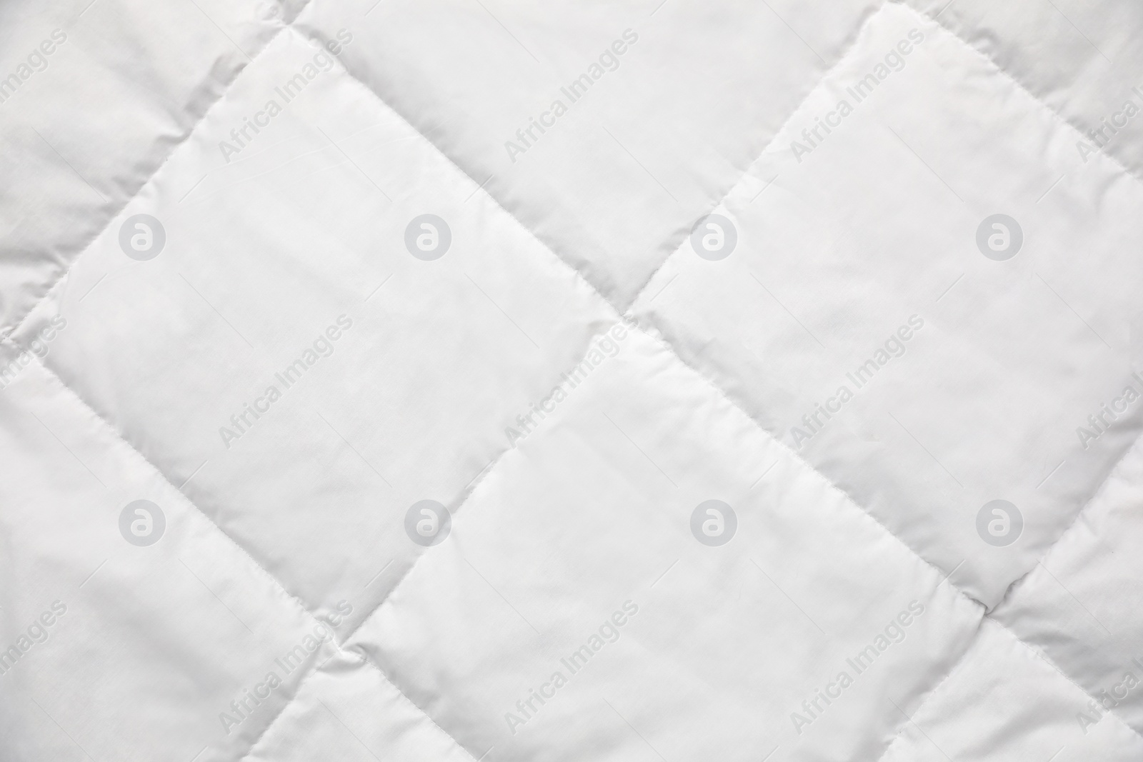 Photo of Soft quilted blanket as background, top view