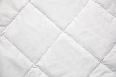 Photo of Soft quilted blanket as background, top view