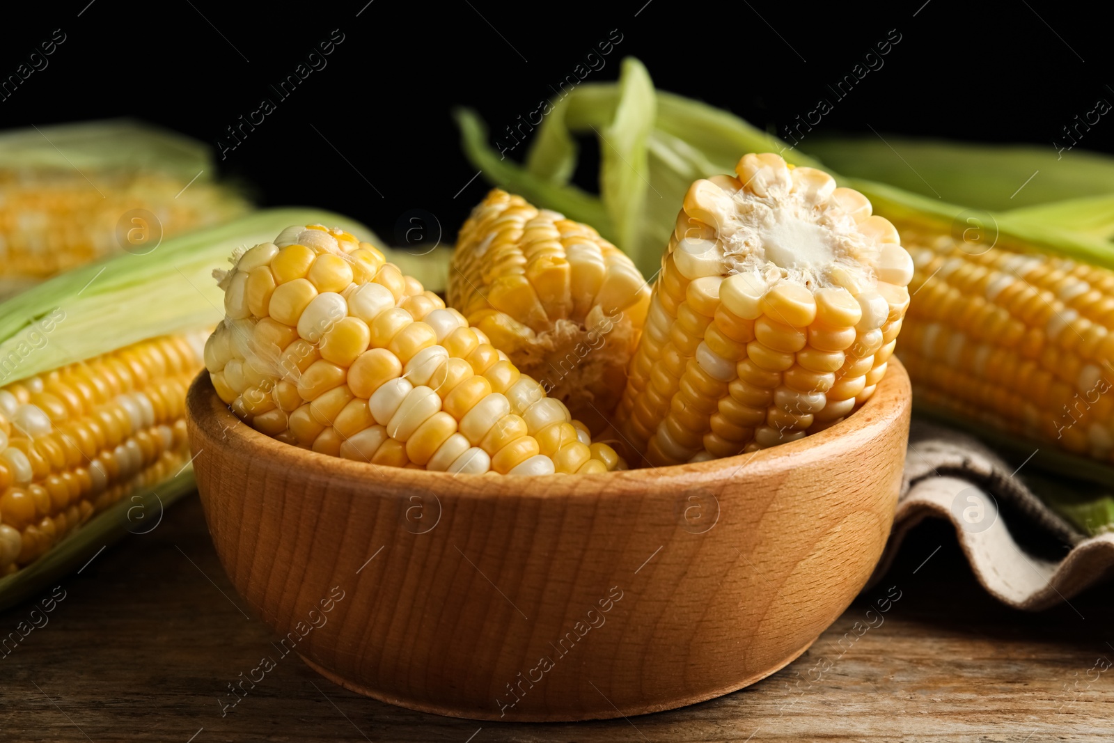 Photo of Tasty sweet corn cobs on wooden table, closeup