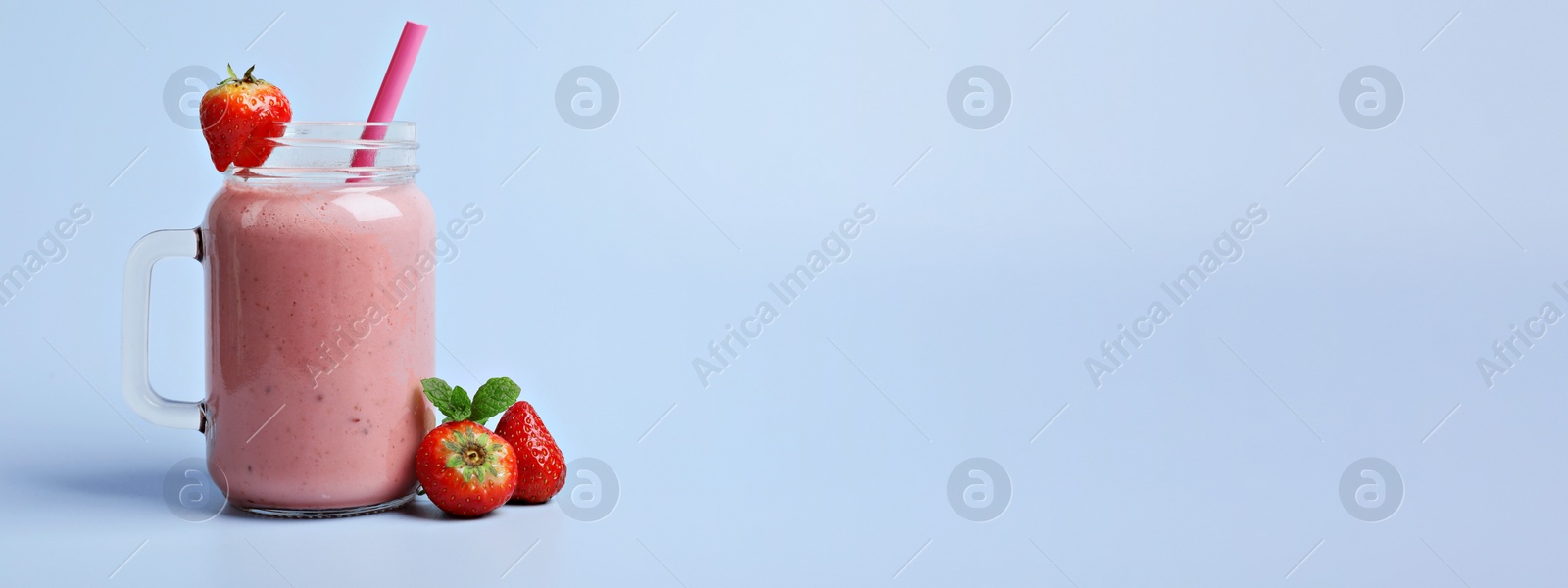 Image of Mason jar with delicious strawberry smoothie and fresh berries on light blue background, space for text. Banner design