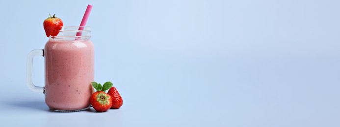 Image of Mason jar with delicious strawberry smoothie and fresh berries on light blue background, space for text. Banner design