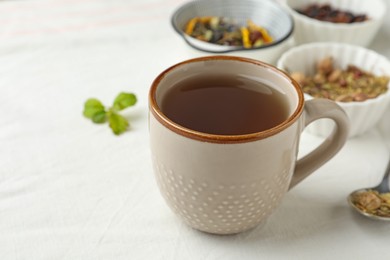 Photo of Cup of hot freshly brewed tea on white fabric, closeup