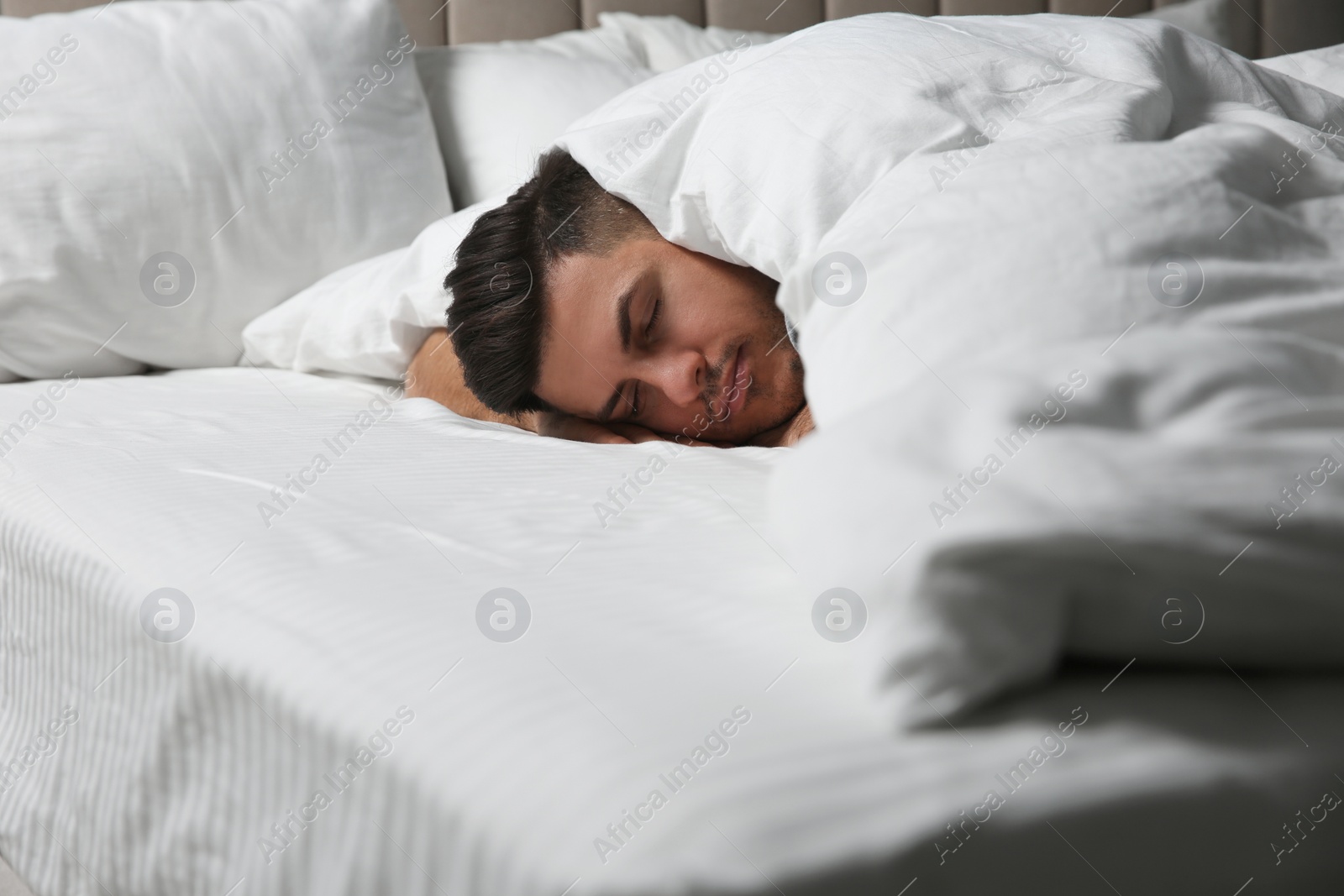 Photo of Handsome man sleeping under soft blanket in bed at home