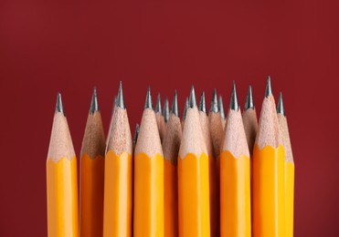 Photo of Many graphite pencils on burgundy background, macro view. Space for text