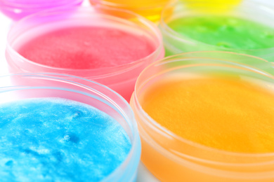 Photo of Colorful slimes in plastic containers, closeup. Antistress toy