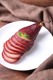 Tasty red wine poached pear on wooden table, closeup