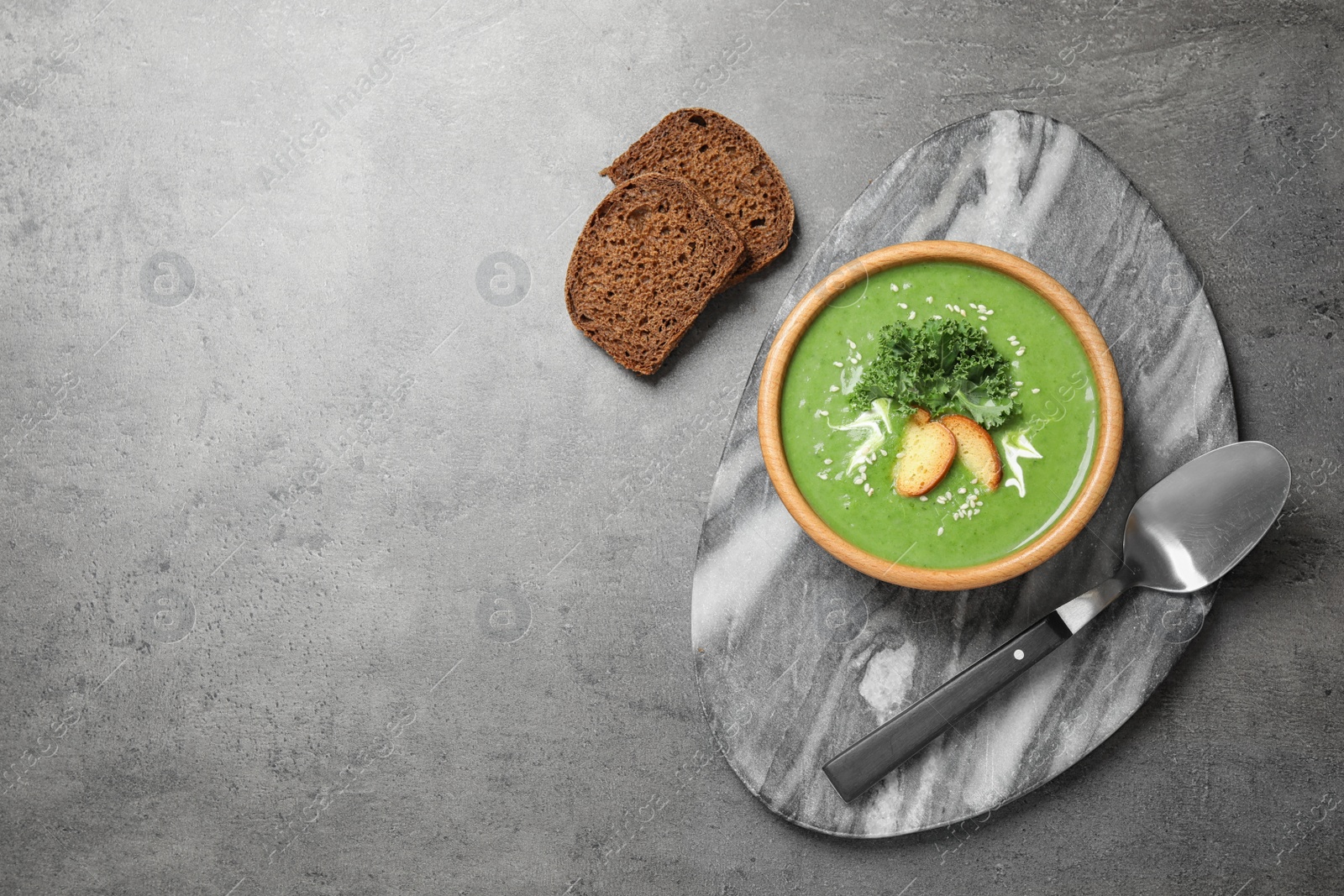 Photo of Tasty kale soup served on grey table, flat lay. Space for text