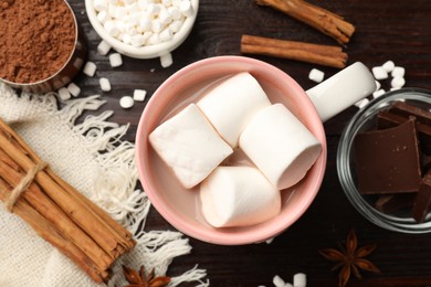 Photo of Tasty hot chocolate with marshmallows and ingredients on wooden table, flat lay