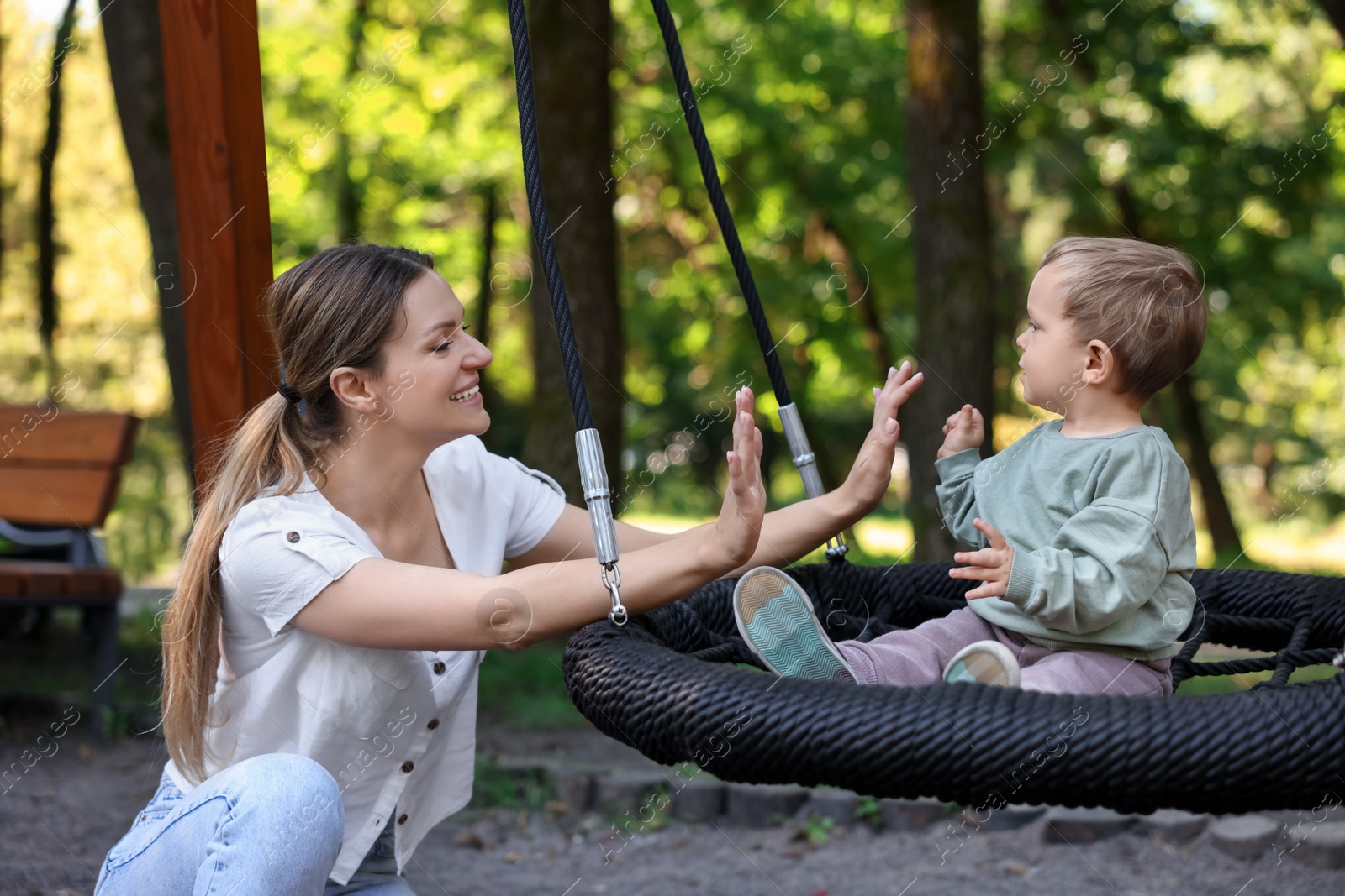 Photo of Happy nanny and cute little boy on swing outdoors