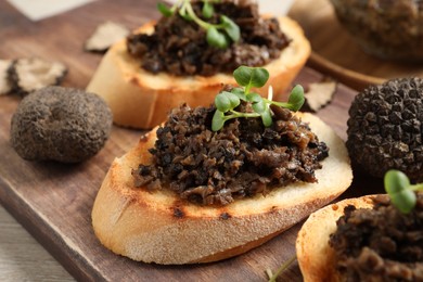 Photo of Delicious bruschettas with truffle sauce and microgreens on wooden board, closeup